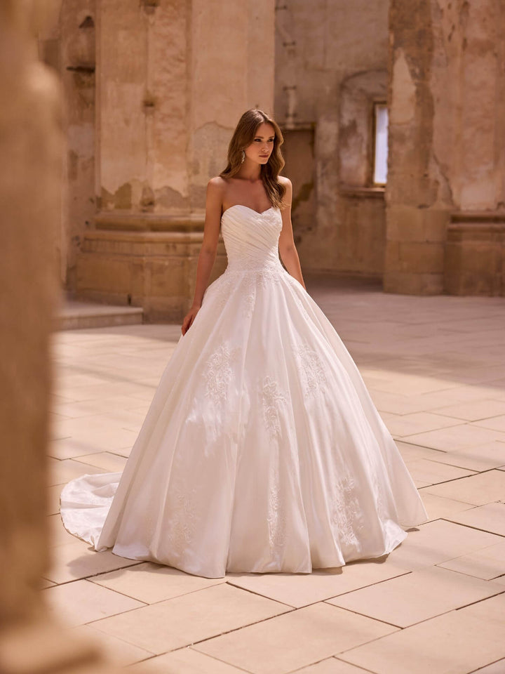 Brudekjole 63019 – frontvisning med klassisk prinsessesilhuet og let shine i stoffet.