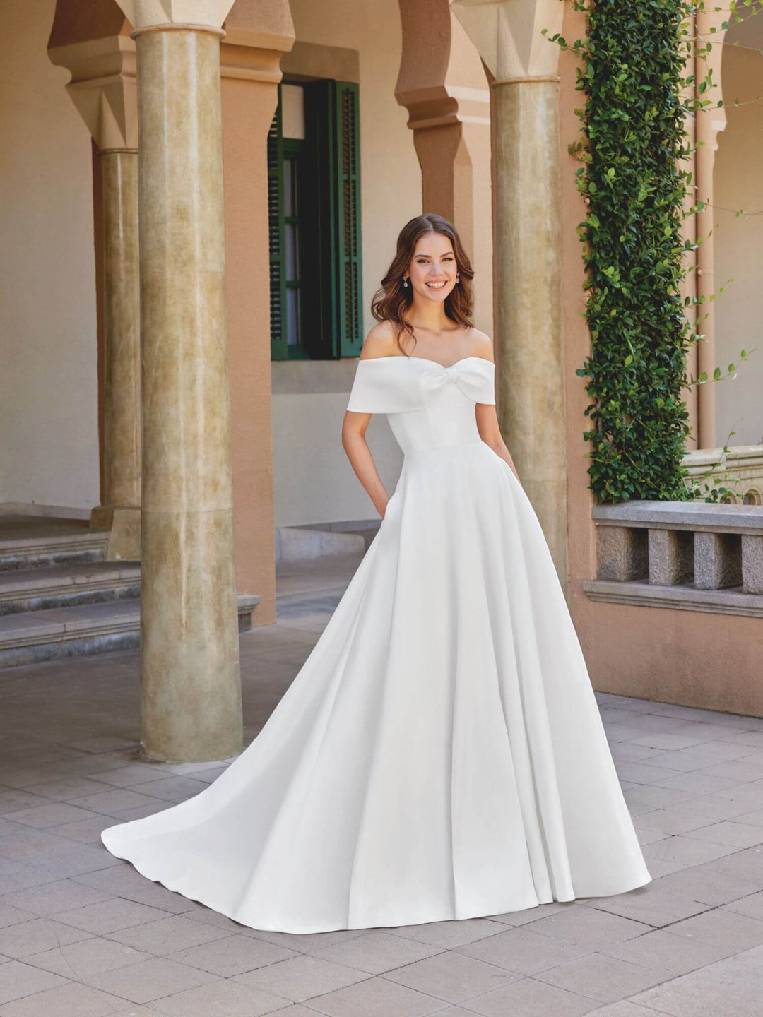 A-line brudekjole i Stretch Mikado med smuk sløjfedetalje og sofistikeret off-shoulder halsudskæring.
