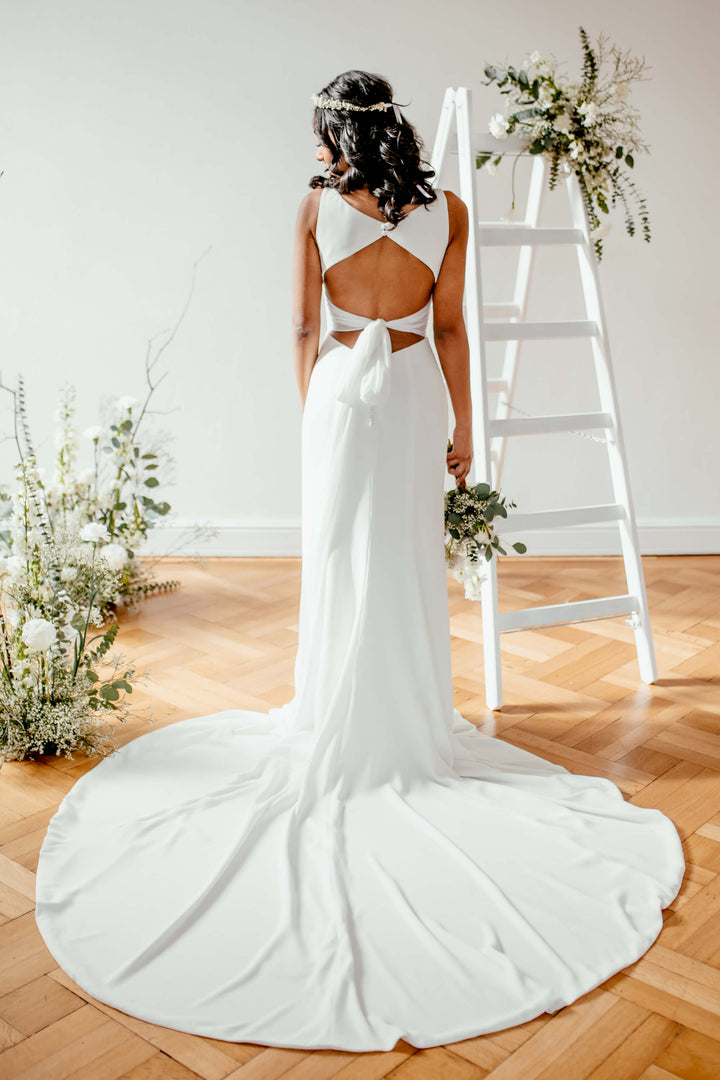 Elegant crepe brudekjole fra Sanna Lindström med Fit & Flare silhuet, markant rygdetalje og minimalistisk nordisk udtryk – Meghan SL1002.